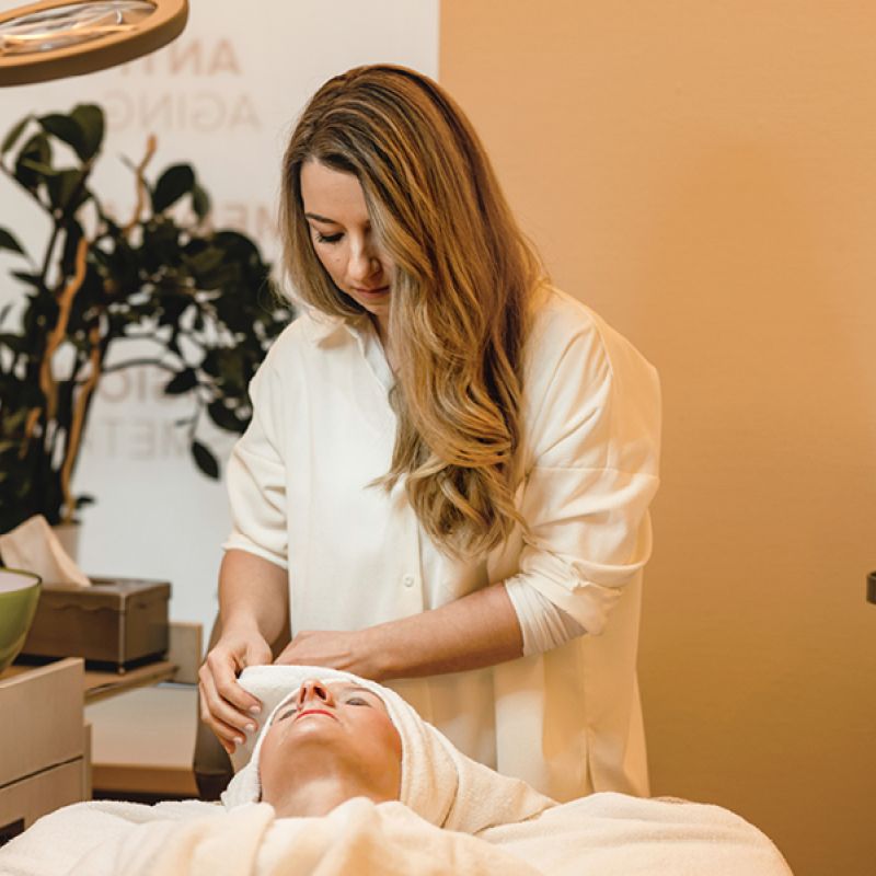 Kosmetikerin in einer Behandlung an einer Kundin auf der Liege