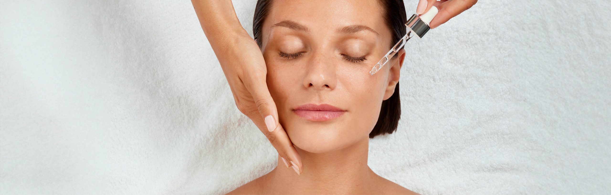 Frau mit geschlossenen Augen, Hand stützt die Wange, Pipette träufelt Serum aufs Gesicht